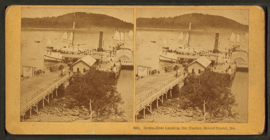 A stereoview of the Bar Harbor steamboat landing with two side-paddle steamboats docked at the wharf, mountains in the background.