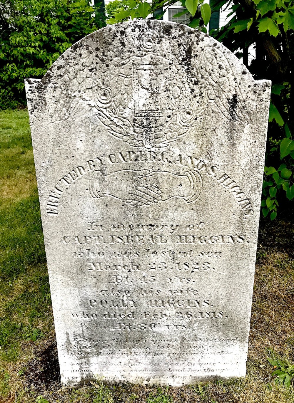 A weathered white marble headstone topped with a winged hourglass carving and a pair of clasped hands. The inscription names Capt. Israel Higgins, lost at sea March 23, 1823, and his wife Polly Higgins, died February 26, 1818.
